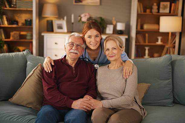 A SevynCare caregiver embracing an elderly couple together on the couch in their home